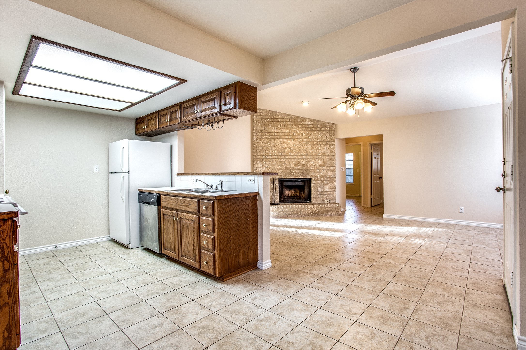 8811 Clearbrook Trail Austin, TX 78729 - Photo 37 of 38 rt B - An inviting open floorplan featuring a kitchen with a bar, seamlessly flowing into a living space with a charming brick fireplace.