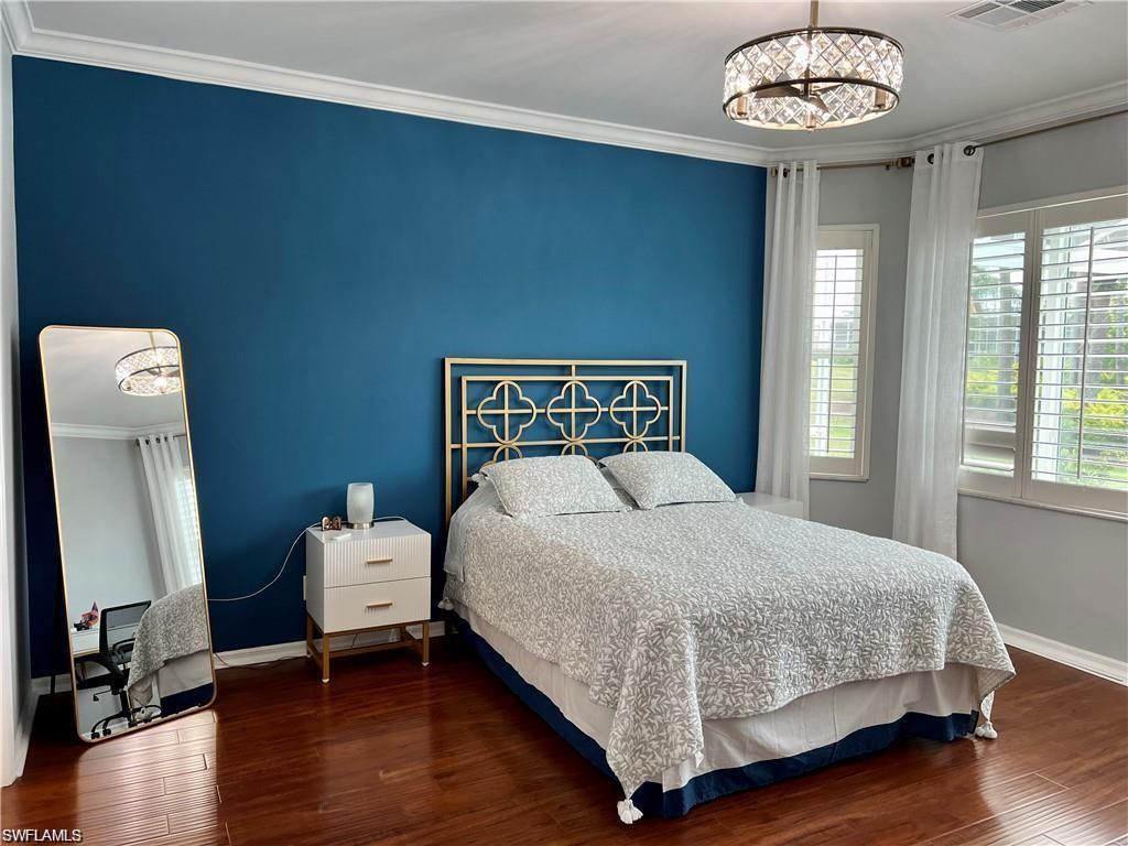 1812 Avian Court, Unit A78 Naples, FL 34119 - Photo 11 of 19 a bedroom with a bed and a chandelier