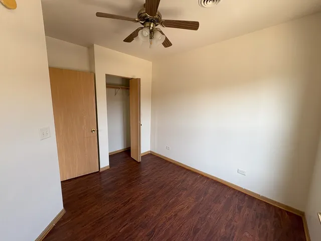 an empty room with wooden floor closet and windows