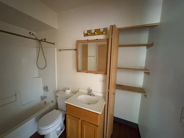 a bathroom with a toilet sink vanity tub and shower