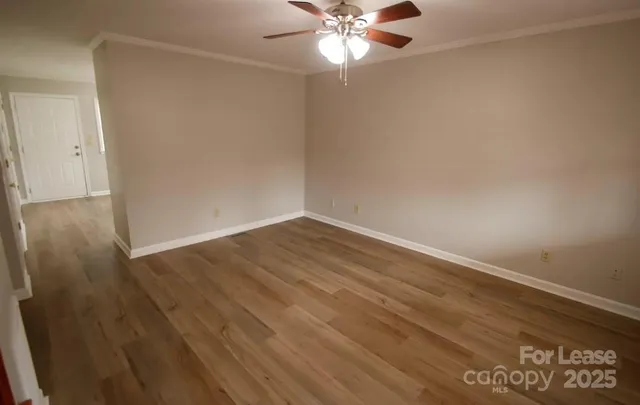 an empty room with wooden floor and fan