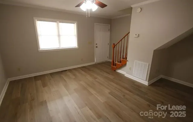 a view of an empty room with wooden floor and a window