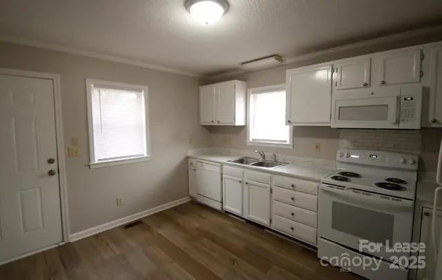 a kitchen with granite countertop white cabinets and white appliances