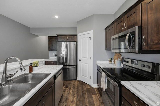 2483 South 1296th Street West Logan, UT 84321 - Photo 9 of 45 Kitchen featuring wood-finish flooring, dark wood cabinetry, stainless steel appliances, and white marble-look countertops