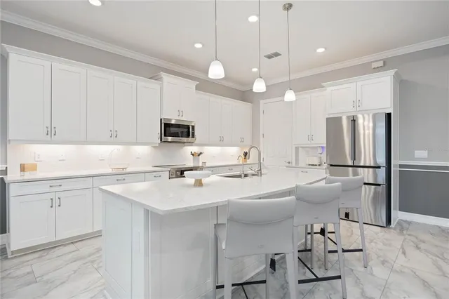 a large white kitchen with kitchen island a sink a stove a refrigerator and a cabinets