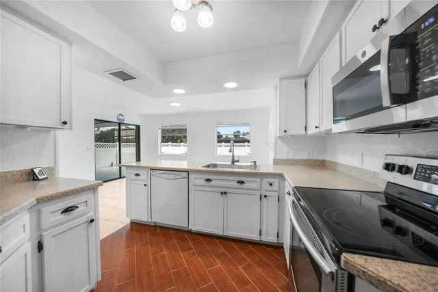 a kitchen with stainless steel appliances granite countertop a stove a sink and a microwave