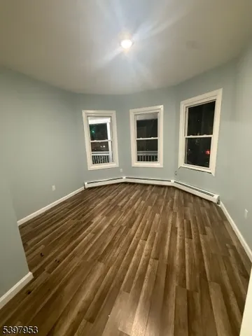 a view of an empty room with wooden floor and window