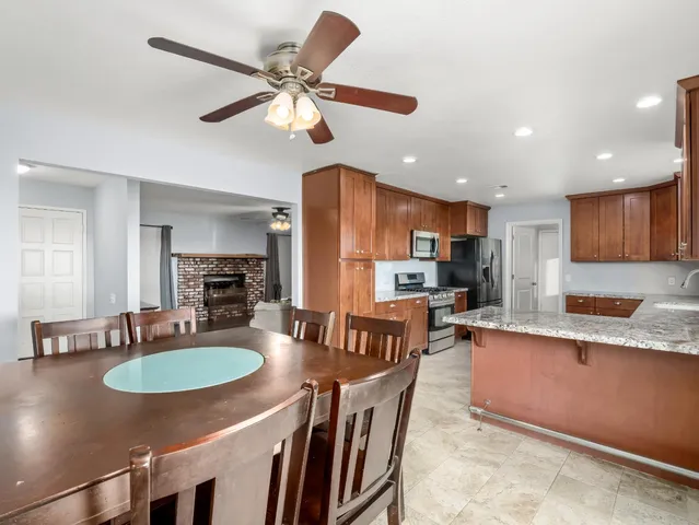 a kitchen with stainless steel appliances granite countertop a sink a stove a dining table and chairs