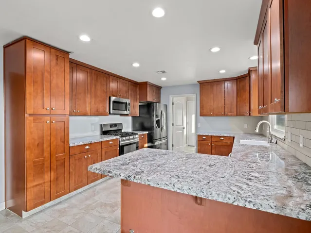 a kitchen with stainless steel appliances granite countertop a sink refrigerator stove and microwave