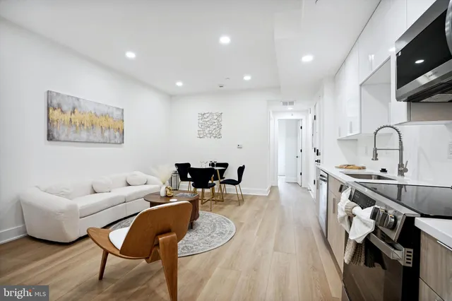 a living room with furniture a flat screen tv and kitchen view