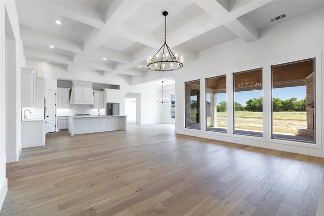 a view of an empty room with wooden floor fireplace and a window