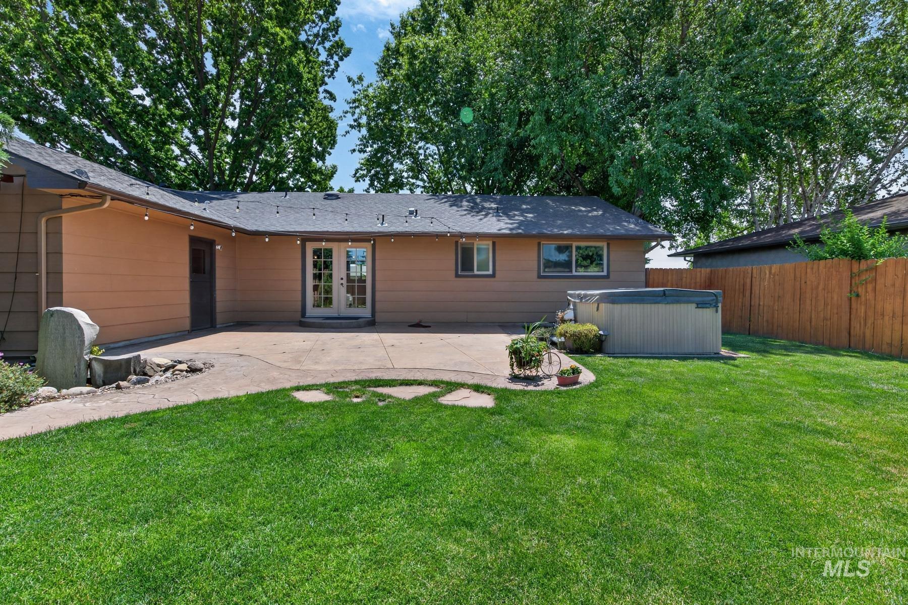9622 Delaware Street Boise, ID 83709 - Photo 34 of 48 Manicured lawn with a concrete patio featuring double french doors, a built-in hot tub, and a privacy fence