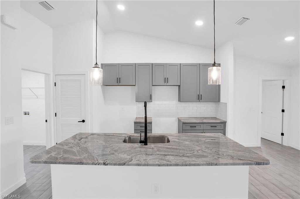 2719 29th Street Southwest Lehigh Acres, FL 33976 - Photo 2 of 23 a kitchen with kitchen island a counter top space a sink and cabinets