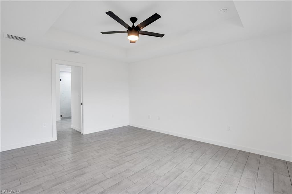 2719 29th Street Southwest Lehigh Acres, FL 33976 - Photo 6 of 23 an empty room with wooden floor and a ceiling fan