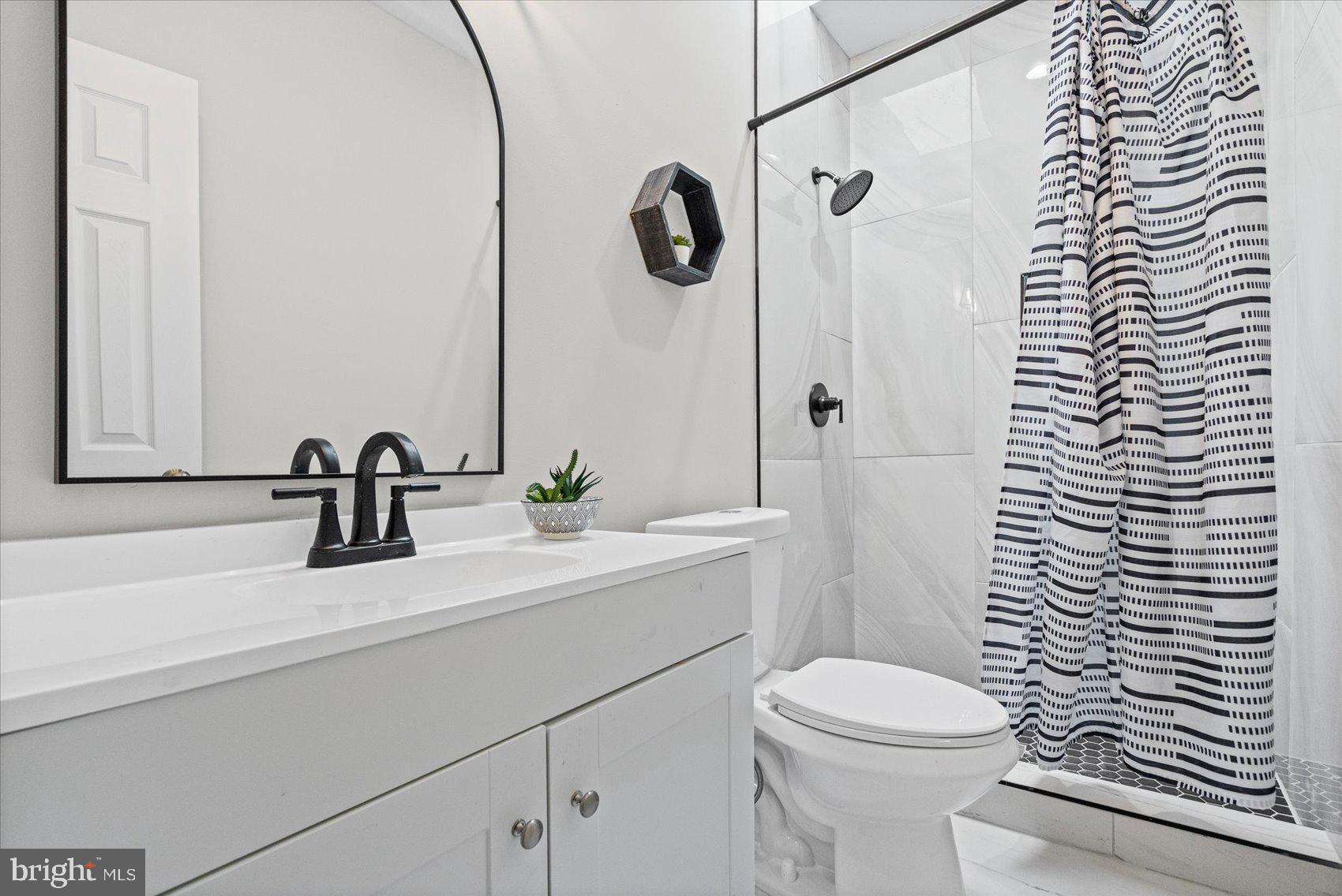 13 South Hilton Street Baltimore, MD 21229 - Photo 31 of 48 a bathroom with a sink a toilet a mirror and shower