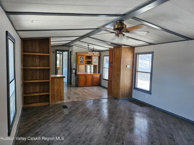 a view of a livingroom with wooden floor a ceiling fan and windows