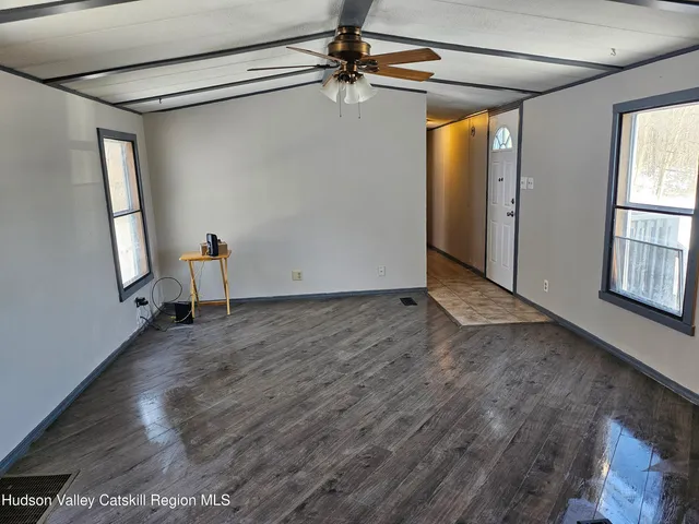 a view of a hallway to room with wooden floor and cabinet