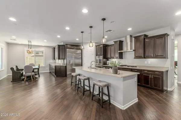 a kitchen with stainless steel appliances kitchen island granite countertop a stove a sink a refrigerator and a dining table with wooden floor