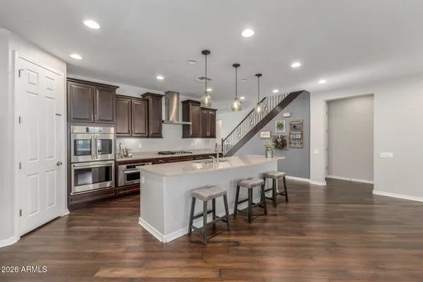 a kitchen with stainless steel appliances granite countertop a refrigerator oven a stove and a wooden floors