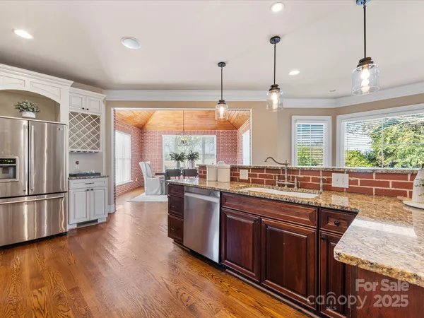 a kitchen with stainless steel appliances granite countertop a refrigerator a sink dishwasher a stove and white countertops with wooden floor