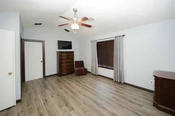 an empty room with wooden floor chandelier fan and windows