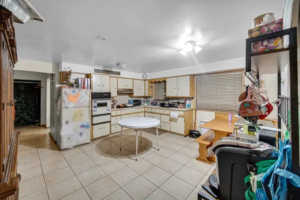 a large white kitchen with a large window and furniture
