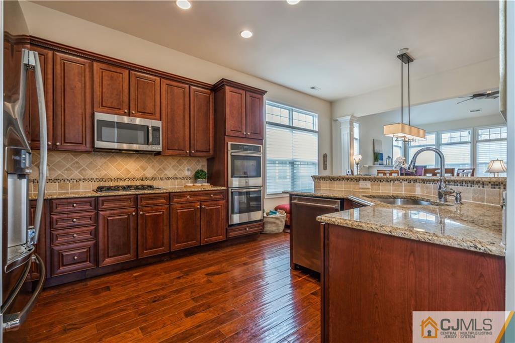 118 Cobblestone Boulevard Monroe Township, NJ 08831 - Photo 8 of 34 a kitchen with stainless steel appliances granite countertop wooden cabinets a stove a sink and dishwasher with wooden floor
