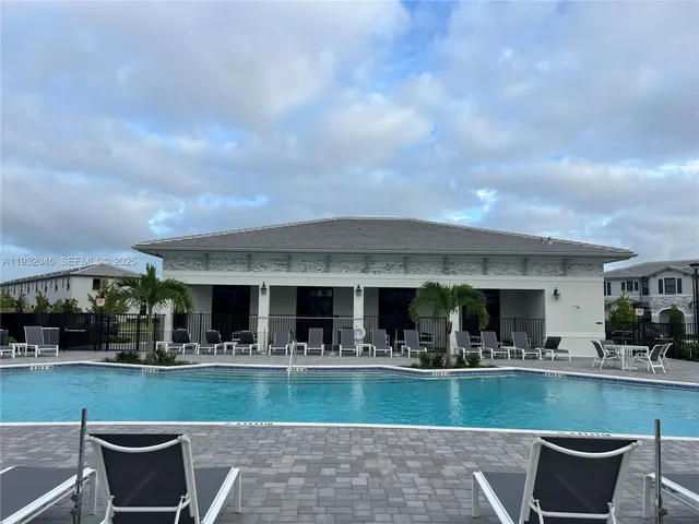 a view of house with swimming pool and outdoor seating