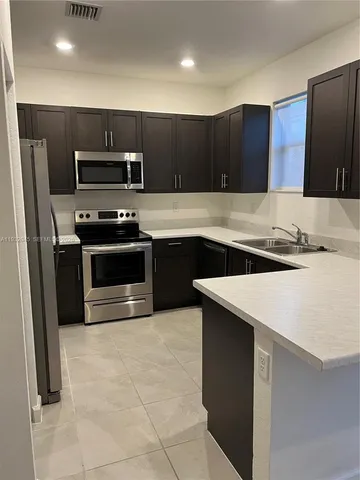 a kitchen with stainless steel appliances a sink and a refrigerator