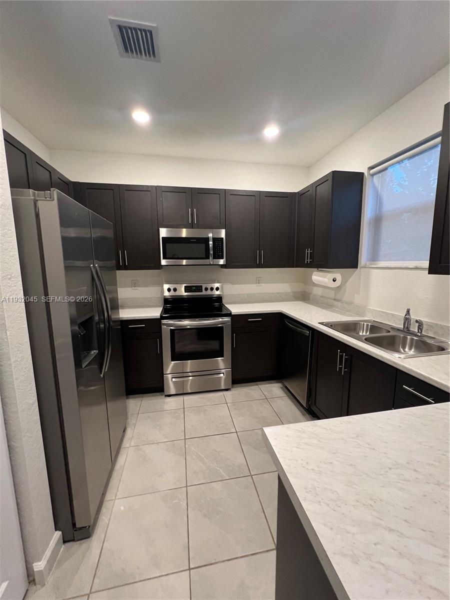 13387 Southwest 287th Terrace Homestead, FL 33033 - Photo 24 of 50 a kitchen with stainless steel appliances granite countertop a sink stove and refrigerator