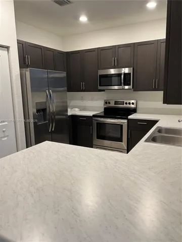 a kitchen with granite countertop a refrigerator and a sink