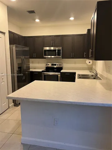 a kitchen with kitchen island stainless steel appliances a sink and a refrigerator