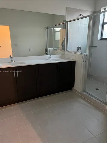 a bathroom with a double vanity sink mirror and shower