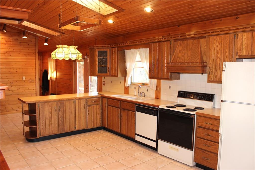 190 Leslie Road Valencia, PA 16059 - Photo 14 of 25 Kitchen view 2 shows oak cabinetry, hanging pan holder, appliances (included) and upper covered deck door access, Eat-in kitchen area located behind wraparound counter.