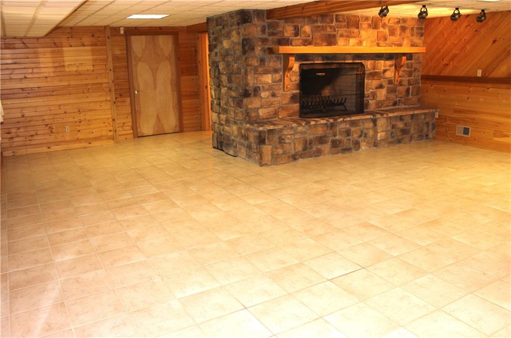 190 Leslie Road Valencia, PA 16059 - Photo 21 of 25 HUGE lower level Family Room features another stone wood burning fireplace w/ spot lighting, cedar & pine walls, ceramic flooring, 3rd full bathroom and access to the lower covered rear patio area.