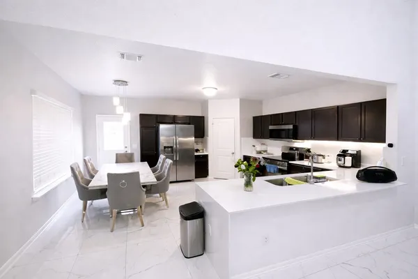 a living room with stainless steel appliances kitchen island granite countertop a kitchen island and a refrigerator