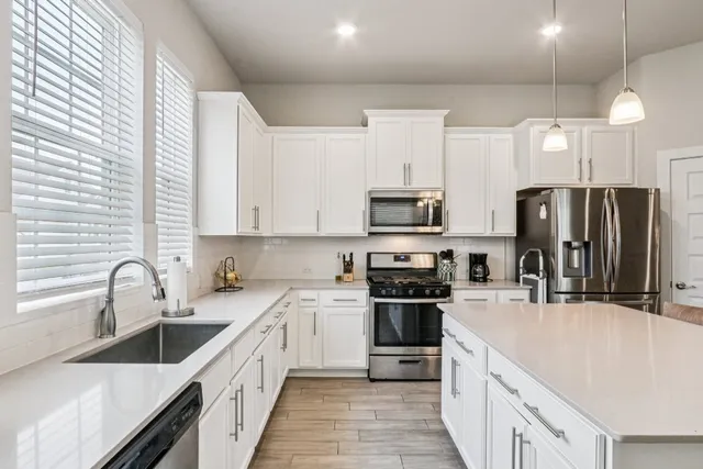 a kitchen with stainless steel appliances a sink stove refrigerator and cabinets