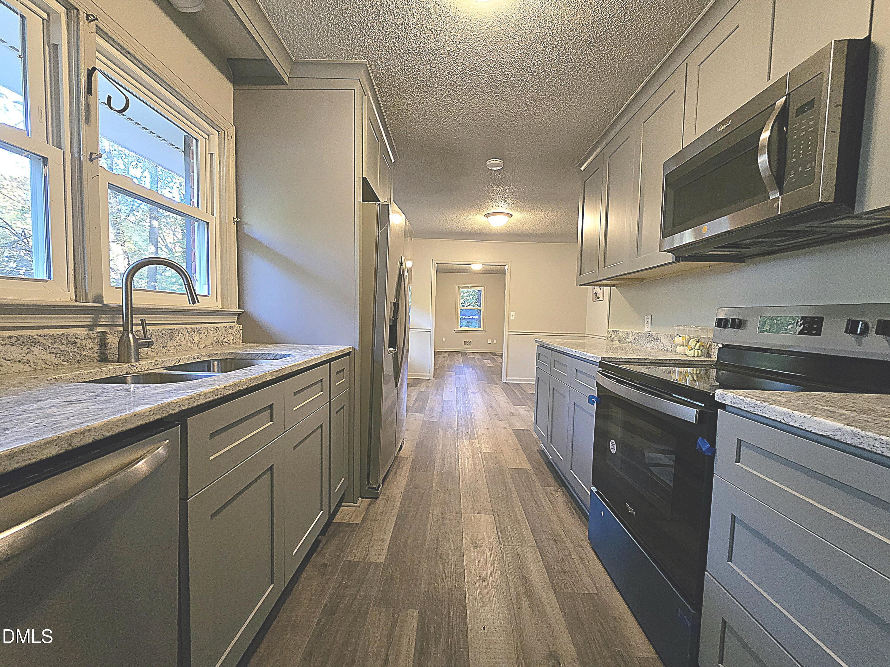807 Grovemont Road Raleigh, NC 27603 - Photo 10 of 22 a kitchen with stainless steel appliances granite countertop wooden cabinets a stove top oven a sink and dishwasher with wooden floor