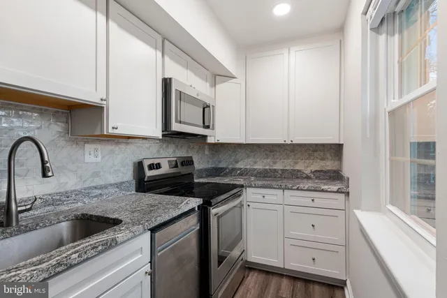 a kitchen with granite countertop white cabinets and stainless steel appliances