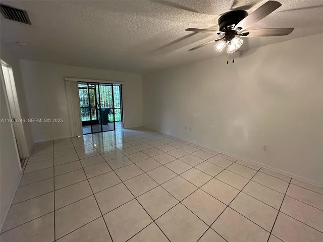 an empty room with windows and ceiling fan