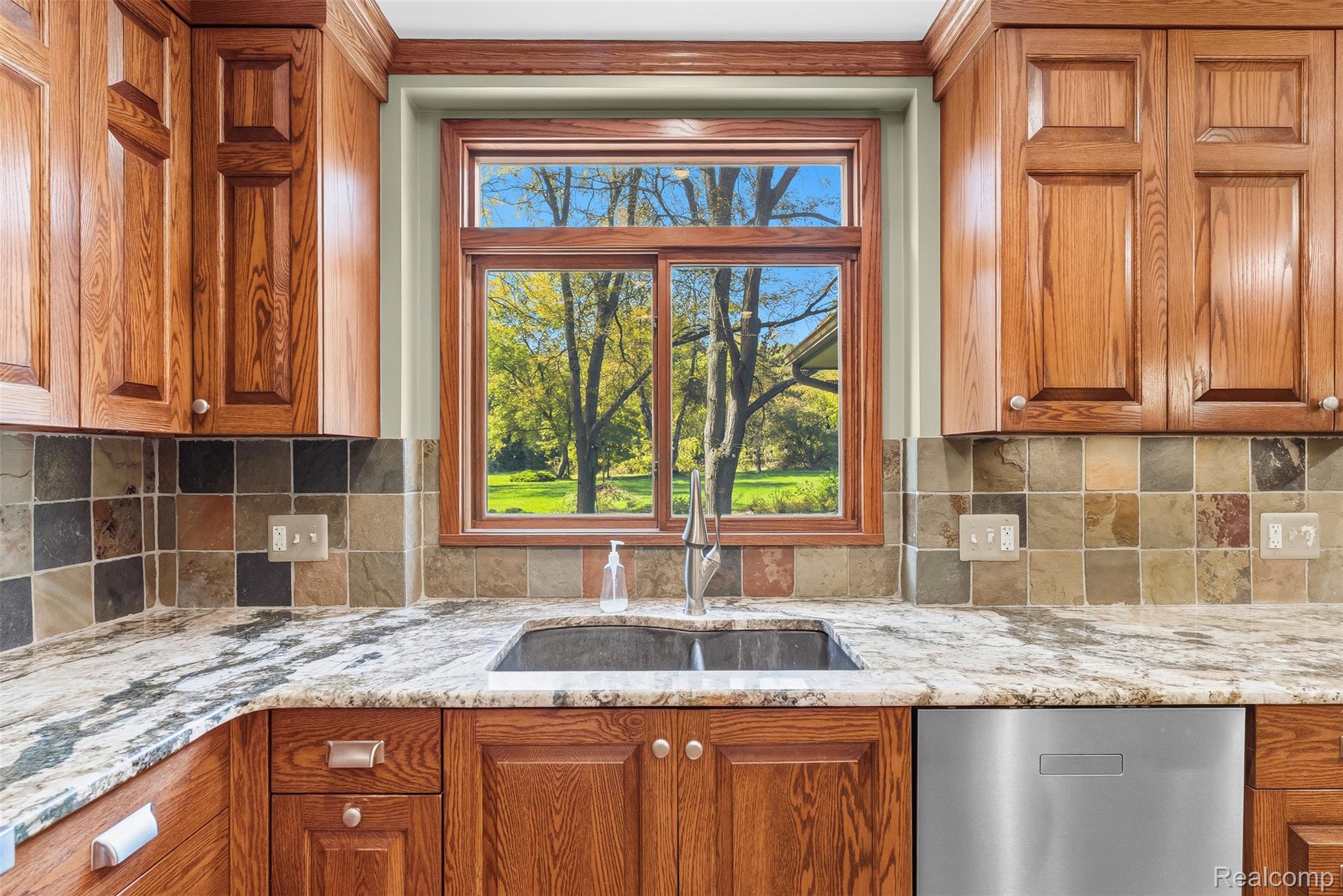8135 Ranch Estates Road Clarkston, MI 48348 - Photo 11 of 53 Granite countertops, wood cabinetry, tile backsplash, stainless steel sink, and a dual-pane window
