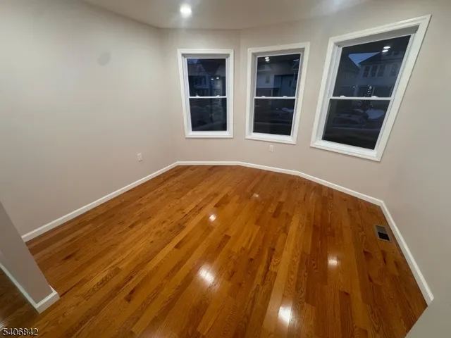 a view of an empty room with wooden floor and windows