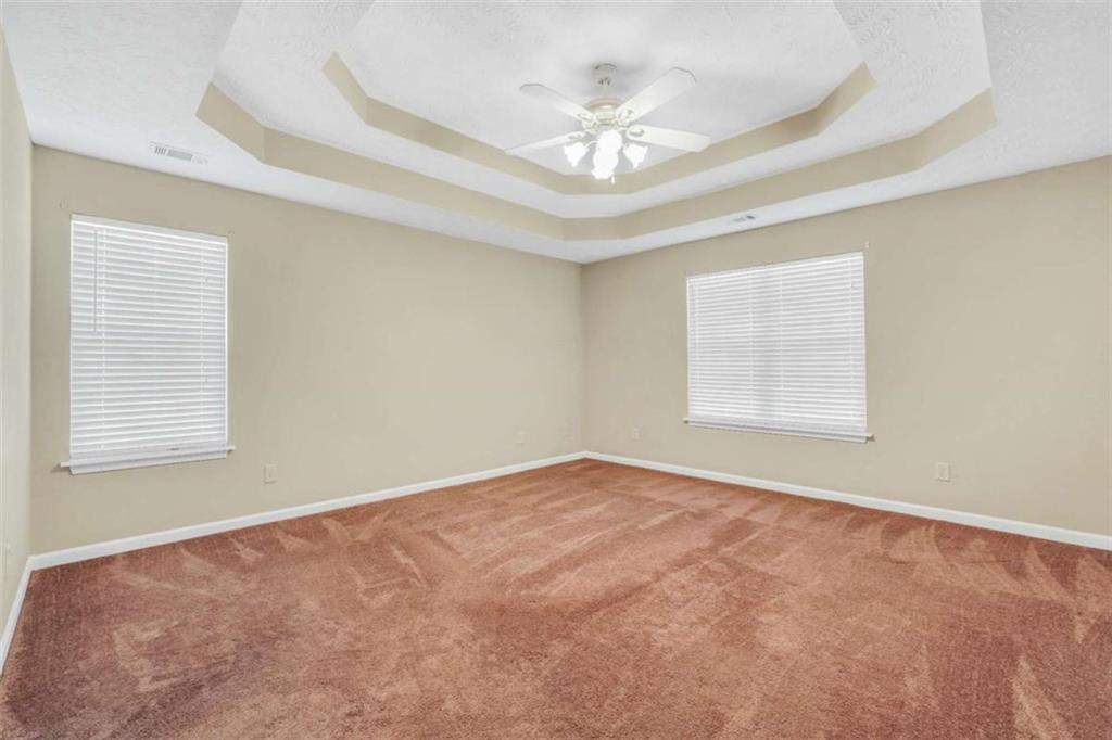 130 Deep Step Road Covington, GA 30014 - Photo 5 of 35 an empty room with a chandelier fan and windows