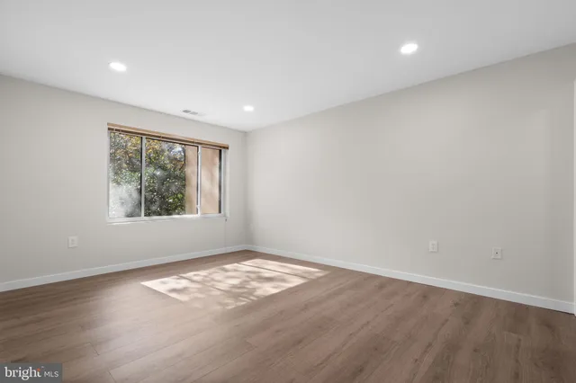 an empty room with wooden floor and windows