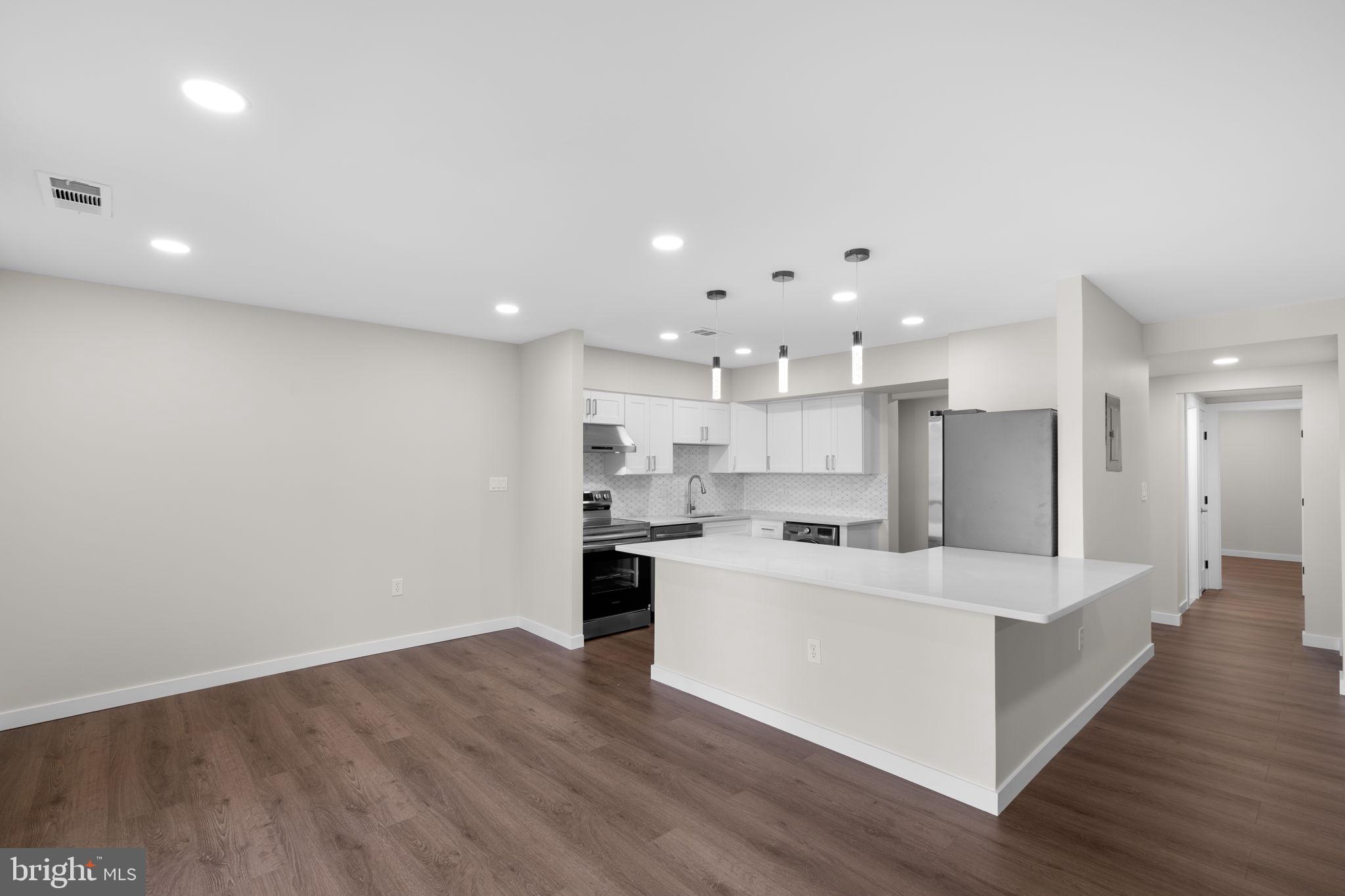 10053 Windstream Drive, Unit 3 Columbia, MD 21044 - Photo 6 of 30 a view of a kitchen with kitchen island a sink wooden floor and a refrigerator