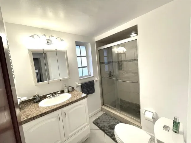 a bathroom with a granite countertop sink toilet and shower