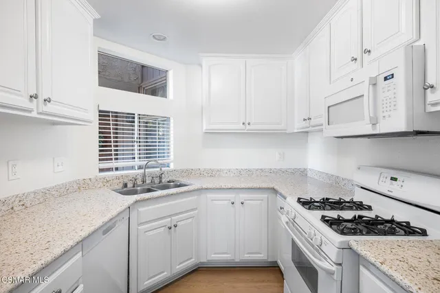 a kitchen with granite countertop white cabinets and appliances