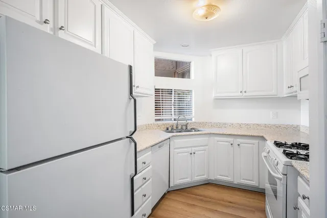 a kitchen with granite countertop a sink cabinets stainless steel appliances and a window