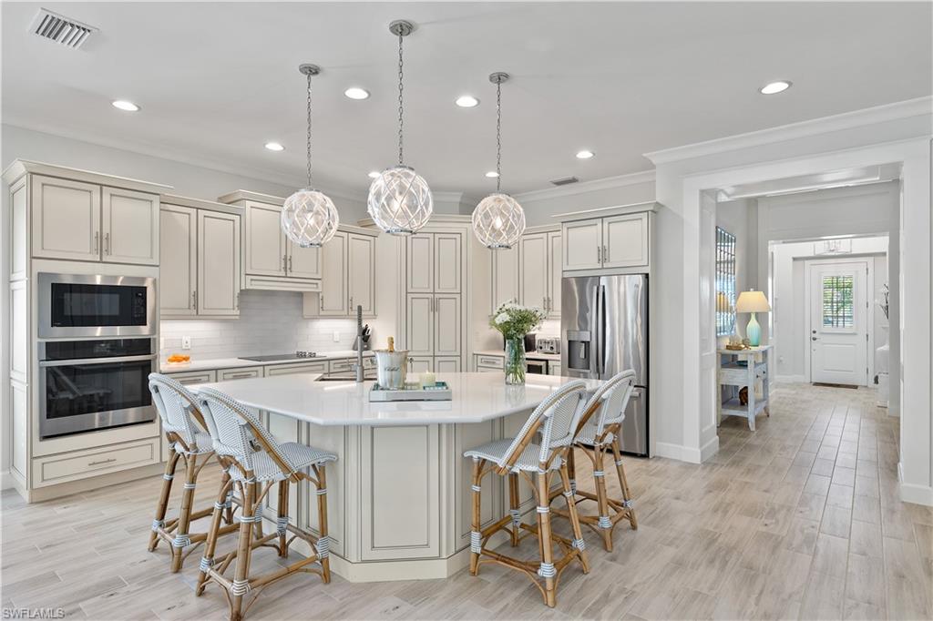 6359 Antigua Way Naples, FL 34113 - Photo 5 of 48 a kitchen with stainless steel appliances a dining table chairs refrigerator and cabinets