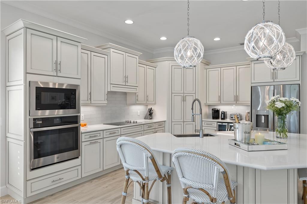 6359 Antigua Way Naples, FL 34113 - Photo 8 of 48 a kitchen with stainless steel appliances granite countertop a sink refrigerator stove and white cabinets